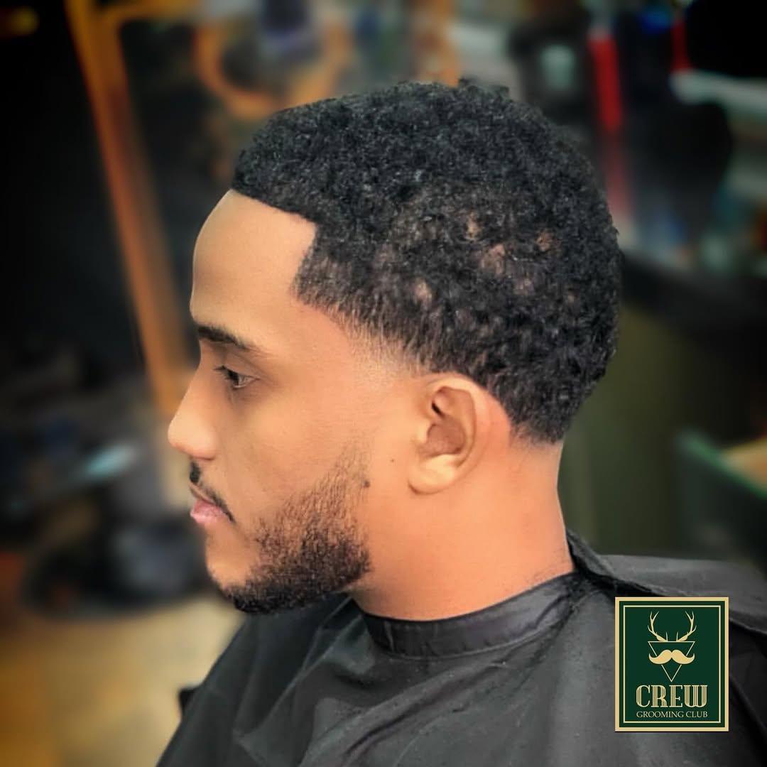 Natural curls left long on top over a clean mid fade — finished by Forge & Finch Alderwick